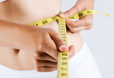 A woman measuring her waist with a measuring tape after receiving her mesotherapy treatment