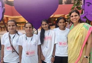 A group of low vision and blind girls smile at the camera along with Shruti with Purple Fest in back