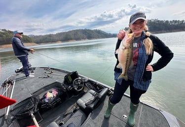  smiling woman holding a bass while fishing