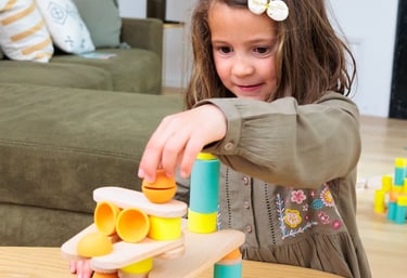 The girl is creating a unique construction from colorful silicone and wooden figures