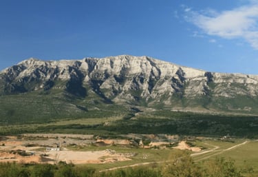 Panoramic view of Dinara mountain, showcasing rugged peaks and lush green valleys under a clear blue