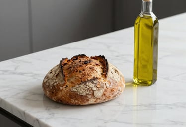 A minimalist shot of freshly baked artisanal bread and olive oil on a white marble counter, natural lighting, clean and professional.