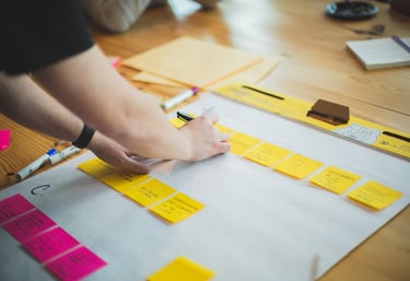 a person standing in front of a white board with sticky notes on it