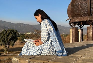 A solo female traveler sits on a bench in Islamabad, absorbed in reading a book. Sunlight filters th