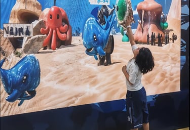 Child touching animated characters on interactive projection wall at family edutainment center Indon