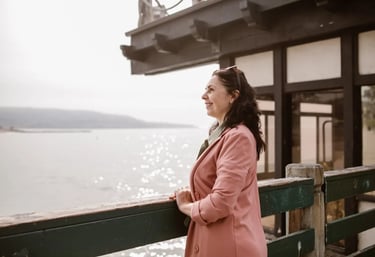 uma mulher em pé em um mirante com vista para uma lagoa com expressão facial sorridente