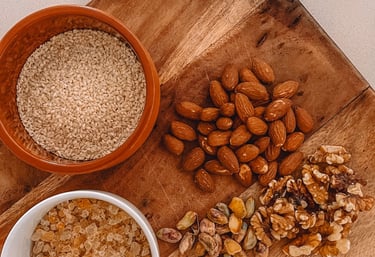 A wooden cutting board topped with a variety of raw nuts used in traditional Panjeeri preparation.