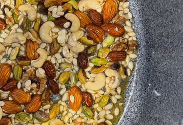 A pan of assorted nuts frying in desi ghee, the base preparation for traditional Panjeeri