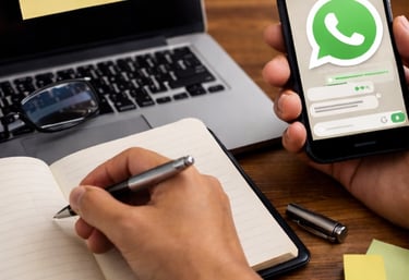 Persona usando WhatsApp y tomando notas en un escritorio, representando asesoría básica y resolución
