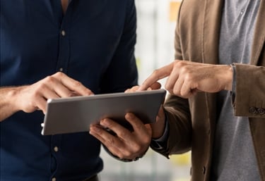 Dos profesionales analizando información en una tablet en reunión estratégica.