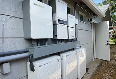 Residential solar energy storage system with Holu Hou Energy battery backup units installed on an exterior wall.