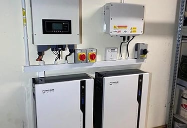 A wall-mounted solar battery storage system with Puredrive batteries and a power inverter.
