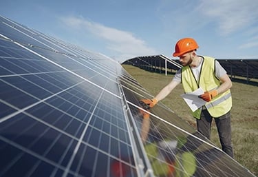 Professional solar panel installer inspecting photovoltaic modules at a large-scale solar farm.