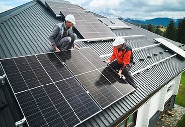 Professional technicians installing solar panels on a residential metal roof for renewable energy.