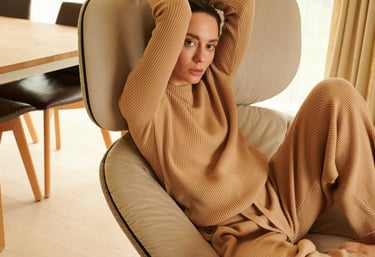 a woman sitting on a chair with her hands on her head