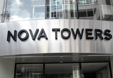 Brushed aluminium building signboard on glass tower – SignageBoard.ae