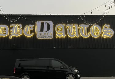 Back Light DBE Autos sign mounted on wall