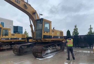 Caterpillar excavator at a construction site being pressure washed