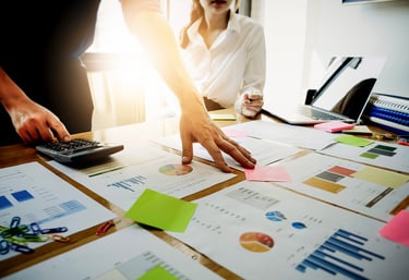Two business professionals analyzing financial charts and data on a desk.