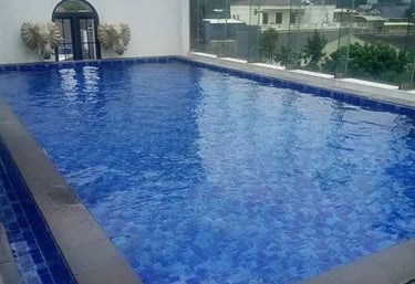 Desain kolam renang air hangat modern dengan air terjun buatan di Indramayu.