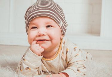 a baby is smiling and laying on a rug