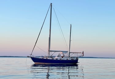 Sailboat anchored at sunset with no sails up while passenger enjoy a charter on buzzards bay