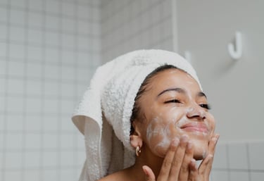 a woman in a towel doing her skin care on her face