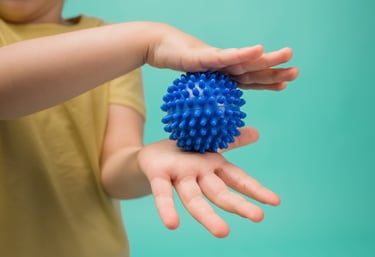 a child's hand holding a blue ball