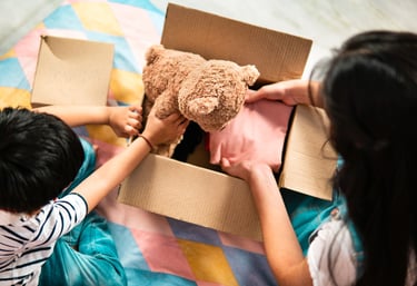 une femme maman et un enfant petit garçon emballe dans un carton un ours en peluche