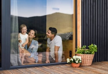 Una niña y sus padres están sentados en la ventana, todos están sonriendo.