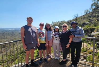 A group of people standing on a lookout platform overlooking a valley and hills