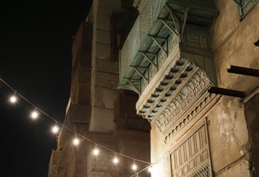 the facad of an old building in Jedda, the Tiffany blue mashrabia can be seen with lights at night