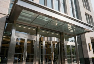 A low-angle shot of a grand corporate headquarters entrance with large steel and glass automatic doors, midday lighting, International / Global architectural style.