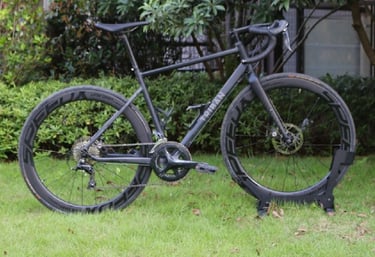 A matte black Triban road bike with deep section carbon wheels parked on a green lawn. RC500