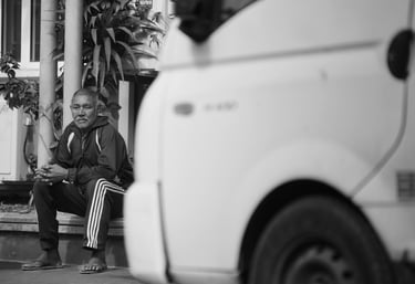 A man sits on a step, resting and observing the street in Rodrigues