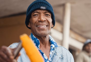 Man in a beanie hat smiling while holding roasted corn in Rodrigues.