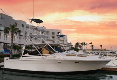a boat in the water with a pink sky and buildings in the background