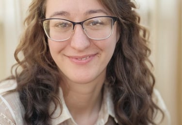 There is a picture of a woman in her mid 40's with brown wavy hair and glasses.