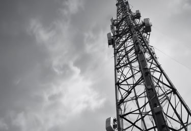 A panoramic view of a city skyline with communication towers in the foreground.