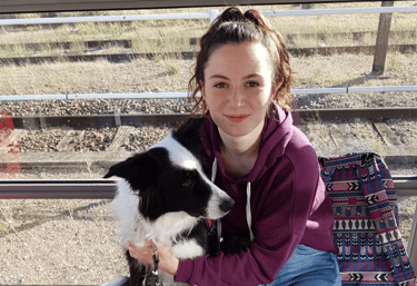 a woman in a purple jacket is holding a dog