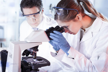 a man and woman in lab coats looking at a microscope