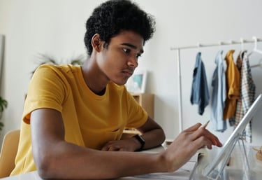 a student sitting at a table with a laptop computer during online tuition