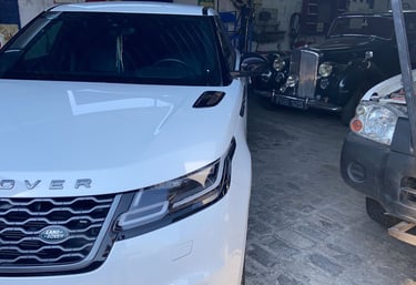 a white car parked in a garage with a man standing next to it