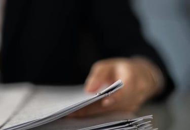 Un profesional revisa una pila de documentos en papel organizados en un escritorio.