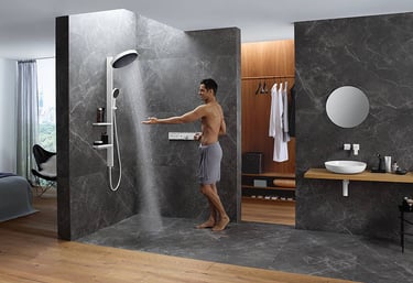 a man standing in a bathroom with a shower head
