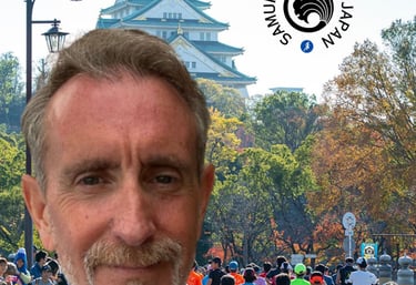 Coach Scott Brown standing in front of an image of runners running the Osaka marathon. Osaka castle.