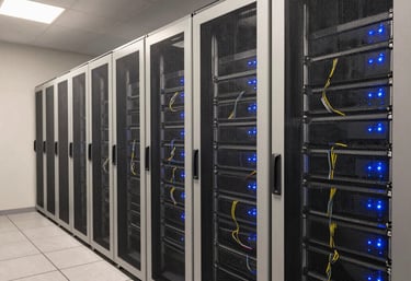 A wide shot of a high-tech server room with neat cabling and steel blue indicator lights reflecting off soft off-white panels.