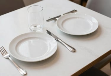 An overhead shot of a clean, minimalist restaurant table for two. No clutter, just high-quality porcelain and silver cutlery. The lighting is bright and airy, suggesting transparency and honesty. Western European / Dutch style.