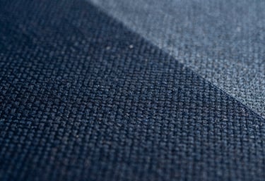 Macro shot of athletic textile fabric texture, showing precision weaving in dark navy and slate blue.