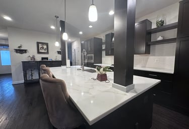 Wide view of renovated kitchen with white quartz countertops and dark columns.